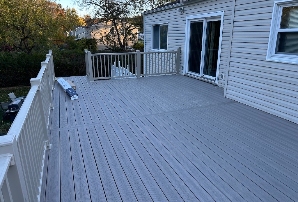Completed grey composite deck with taupe railing overlooking a backyard in Northern New Jersey