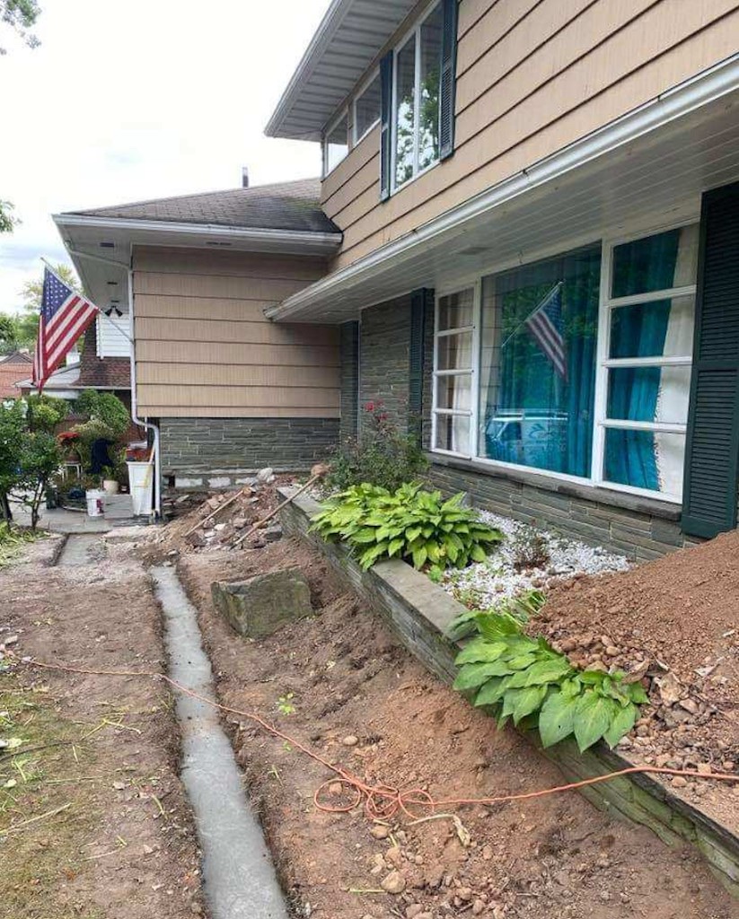 Completed elevated paver patio with light stone coping along a home exterior in Northern New Jersey — before