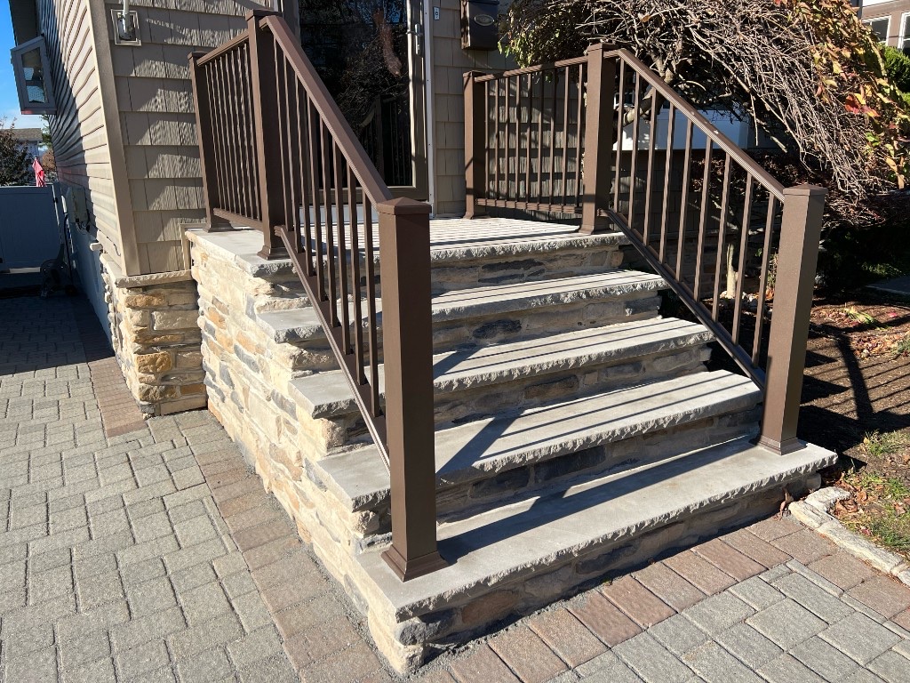 Completed natural stone entry steps with stone veneer risers and metal railings in Northern New Jersey — after