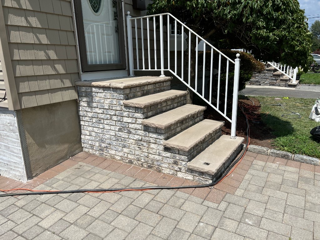 Completed natural stone entry steps with stone veneer risers and metal railings in Northern New Jersey — before